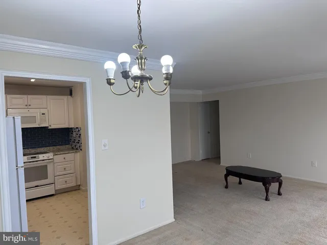 a view of a room with a chandelier and a kitchen