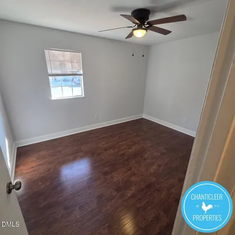 an empty room with wooden floor fan and window