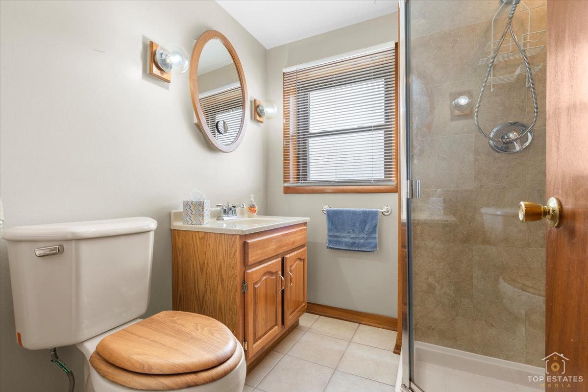 216 Evergreen Street Addison, IL 60101 - Photo 28 of 43 a bathroom with a granite countertop toilet a sink and a mirror