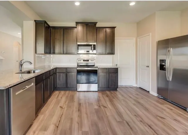 a kitchen with stainless steel appliances granite countertop a sink stove and refrigerator