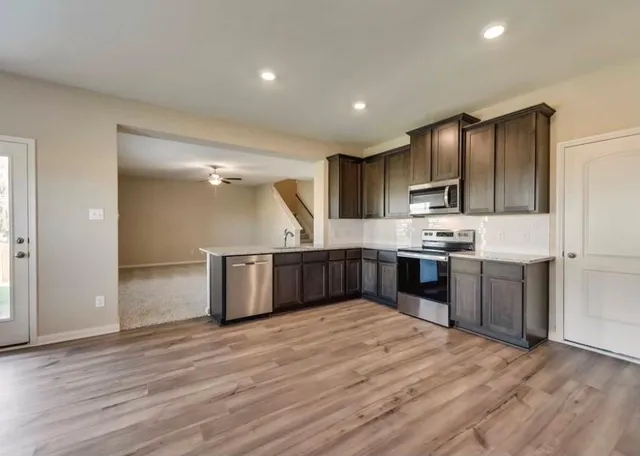 a kitchen with stainless steel appliances kitchen island granite countertop a refrigerator and a stove top oven