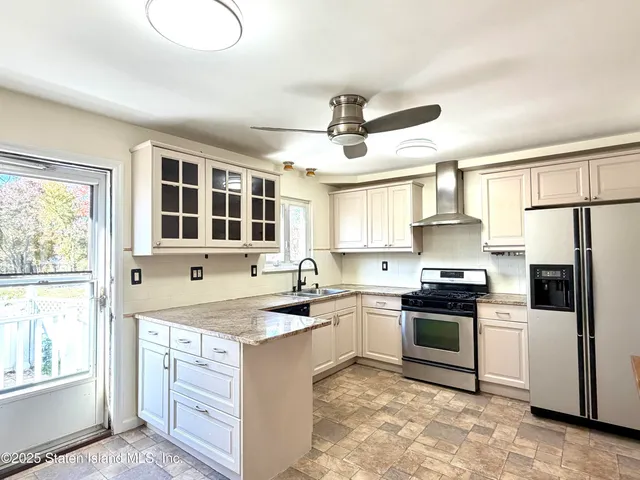 a kitchen with granite countertop a refrigerator a sink and white cabinets