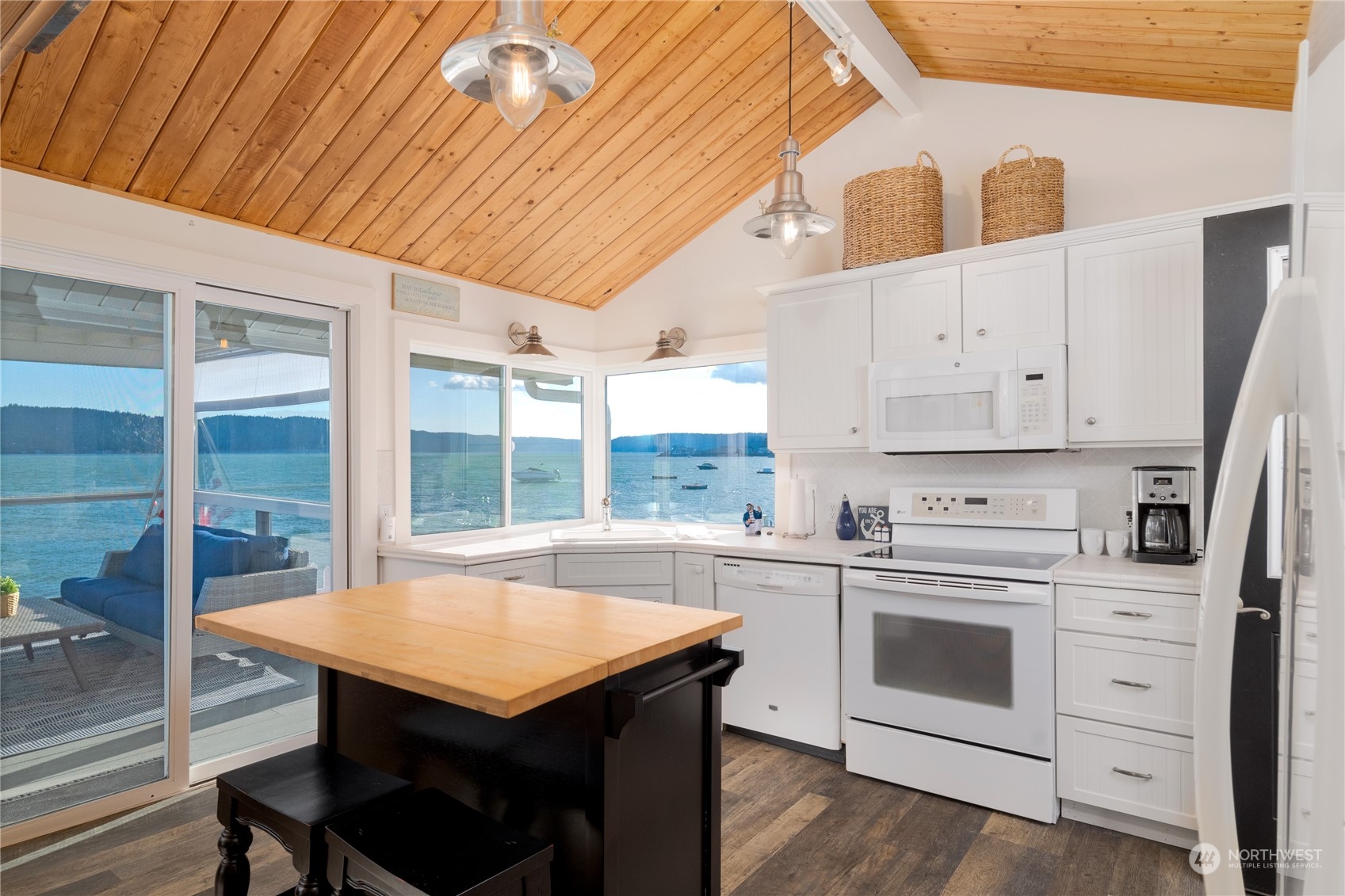 7681 Northeast North Shore Road Belfair, WA 98528 - Photo 17 of 40 a kitchen with a stove a sink dishwasher white refrigerator a dining table and chairs with wooden floor