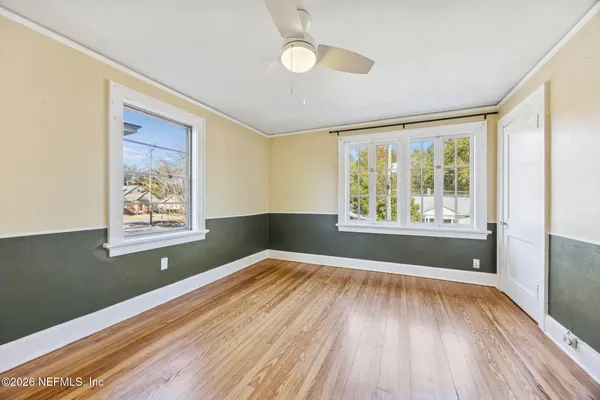 a view of an empty room with wooden floor and a window