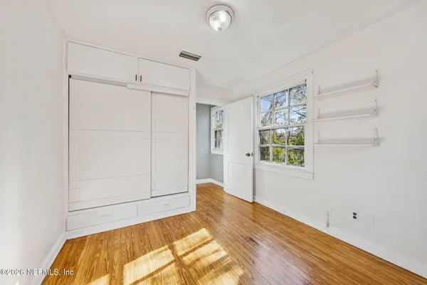 a view of a bedroom with wooden floor and window