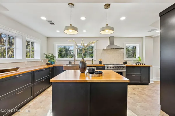 a kitchen with a stove a kitchen island a sink dishwasher a dining table and chairs with wooden floor