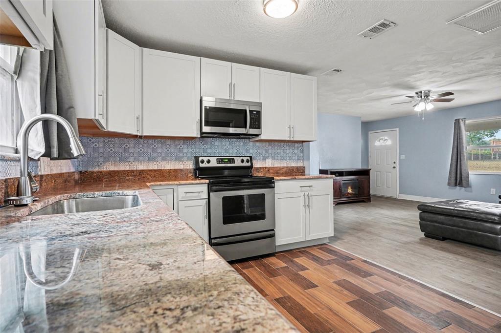 355 South Oak Avenue Frostproof, FL 33843 - Photo 10 of 35 a kitchen with stainless steel appliances granite countertop a stove a sink and a microwave