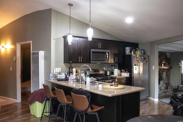 a kitchen with stainless steel appliances kitchen island granite countertop a sink cabinets and wooden floor