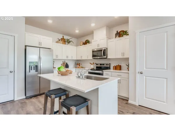 a kitchen with kitchen island white cabinets and stainless steel appliances