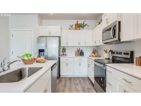 a kitchen with stainless steel appliances a sink a stove top oven a refrigerator a counter top space and cabinets