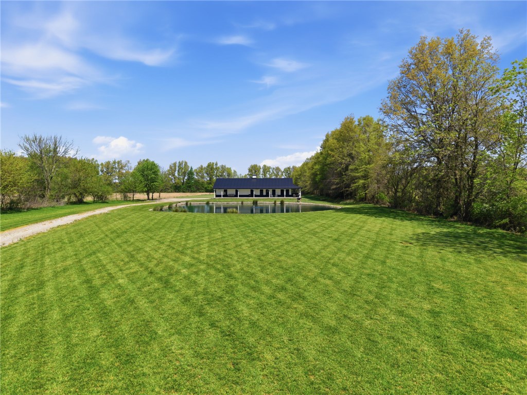 1602 Westboro Road Blanchester, OH 45107 - Photo 64 of 81 A striking modern residence stands beside a tranquil pond, enveloped by expansive green grounds and mature trees.