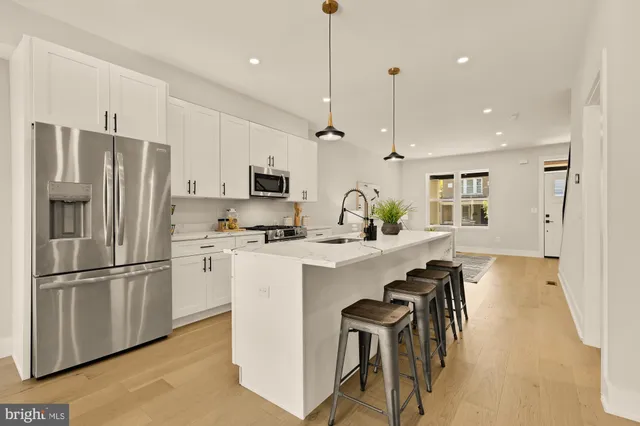 a kitchen with refrigerator a stove a sink and a chairs