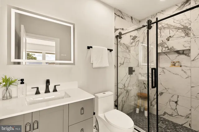 a bathroom with a sink vanity granite toilet and shower