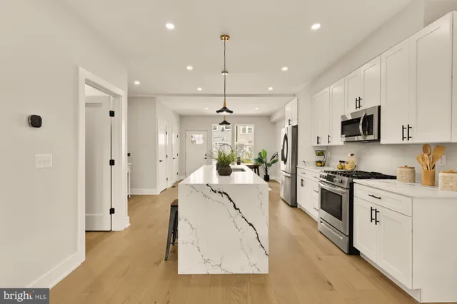 a large white kitchen with stainless steel appliances granite countertop lots of white cabinets and white appliances