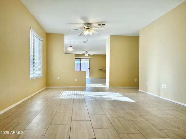 a view of an empty room with window and chandelier fan