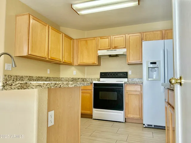 a kitchen with stainless steel appliances granite countertop a refrigerator sink and stove