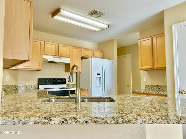 a kitchen with kitchen island granite countertop a stove and a refrigerator