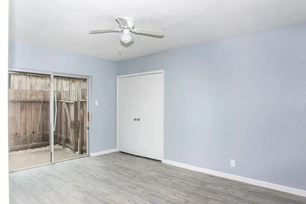 an empty room with wooden floor cabinet and a ceiling fan