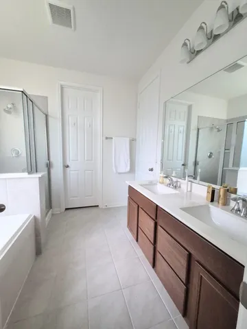 a spacious bathroom with a double vanity sink a mirror and a bathtub