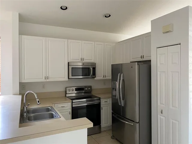 a kitchen with stainless steel appliances a refrigerator a sink a stove a microwave and cabinets