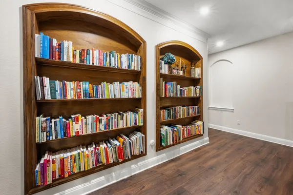 a wooden floor with book shelf and a painting on the wall