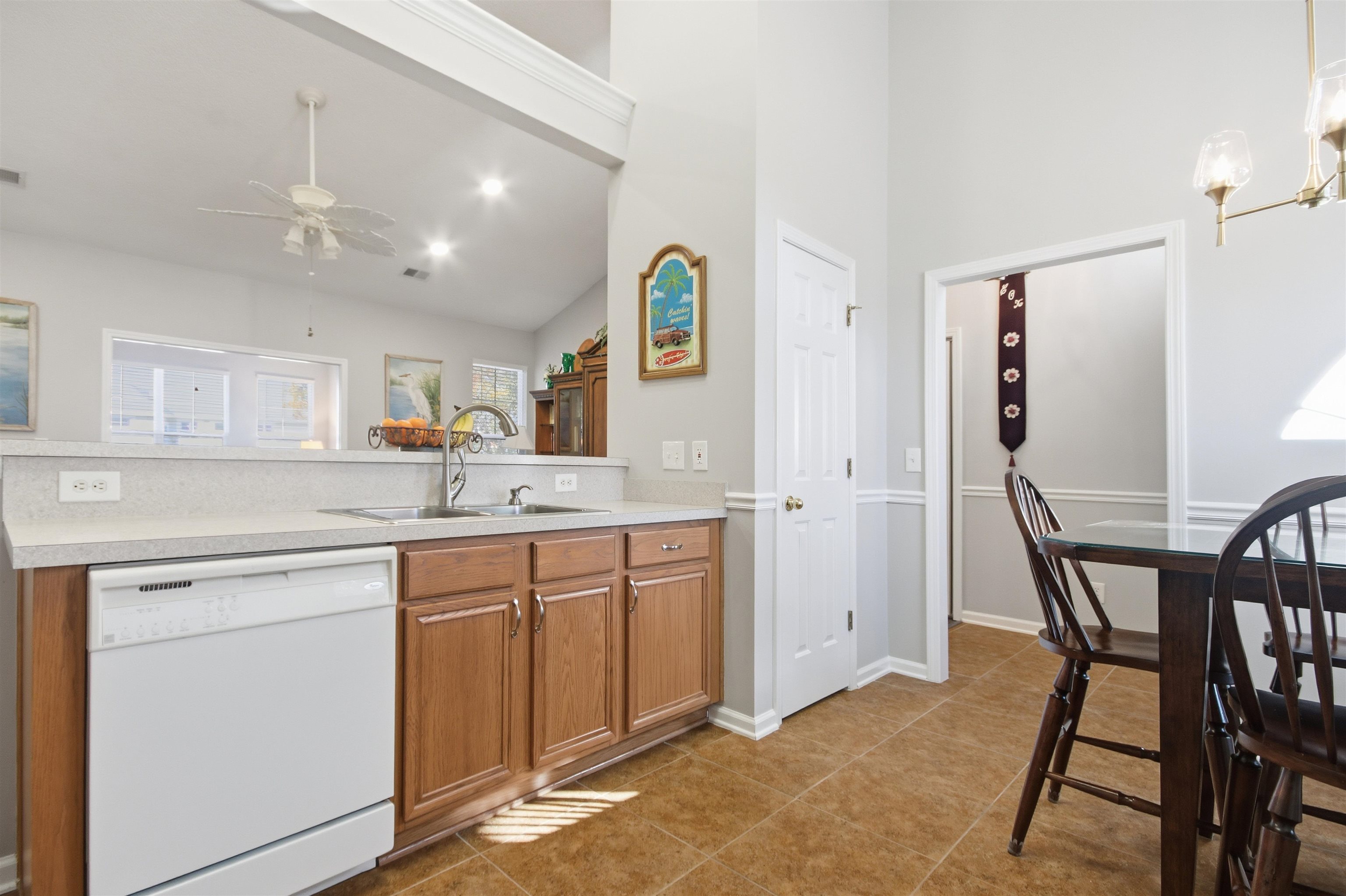 4 Guillemont Court Murrells Inlet, SC 29576 - Photo 5 of 40 Kitchen featuring brown cabinets, white dishwasher, light countertops, dark tile patterned floors, and a chandelier