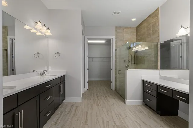 a bathroom with a double vanity sink a large mirror and shower