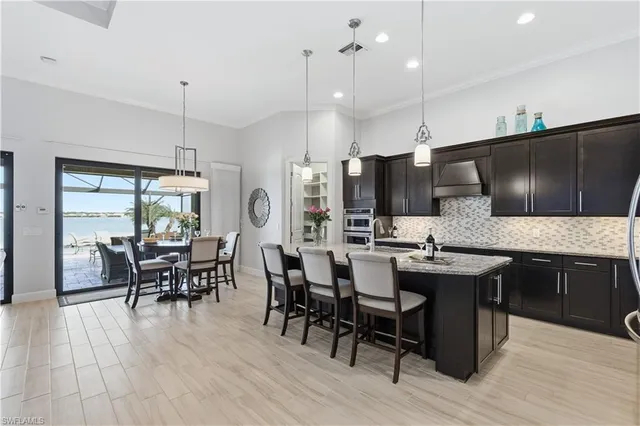 a kitchen with stainless steel appliances granite countertop a table chairs stove and refrigerator