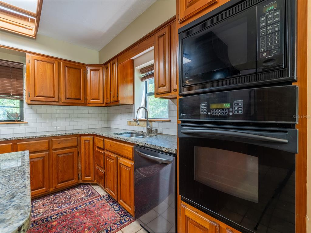 23610 Northeast 154th Place Road Fort McCoy, FL 32134 - Photo 12 of 44 a kitchen with granite countertop stainless steel appliances a stove sink and microwave
