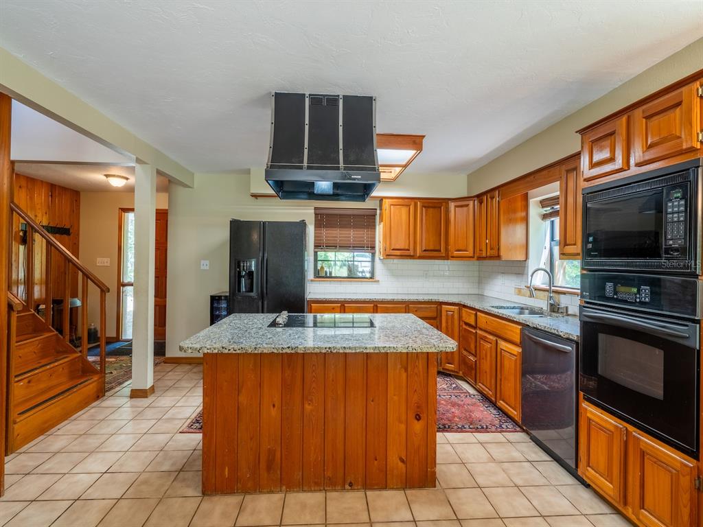 23610 Northeast 154th Place Road Fort McCoy, FL 32134 - Photo 13 of 44 a kitchen with stainless steel appliances granite countertop a sink and a stove