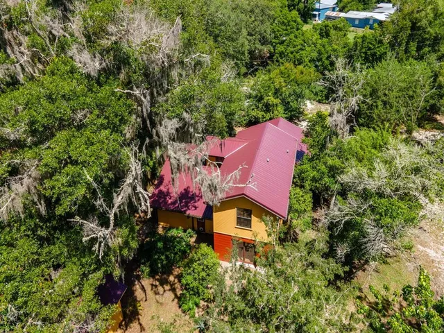 an aerial view of residential house with outdoor space and trees all around
