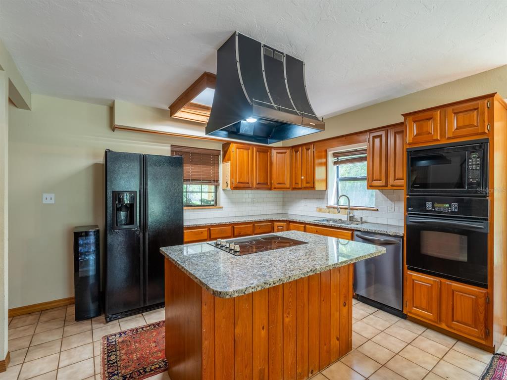23610 Northeast 154th Place Road Fort McCoy, FL 32134 - Photo 10 of 44 a kitchen with stainless steel appliances granite countertop a sink and a refrigerator