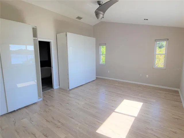 an empty room with wooden floor and windows