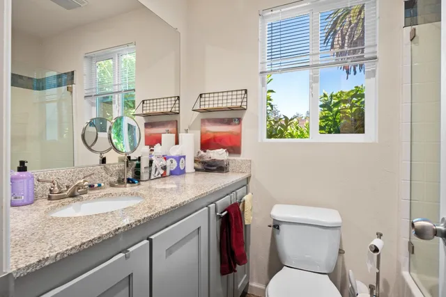 a bathroom with a granite countertop sink mirror vanity and toilet