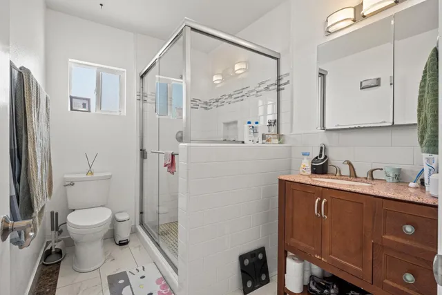a bathroom with a sink a toilet a mirror and shower