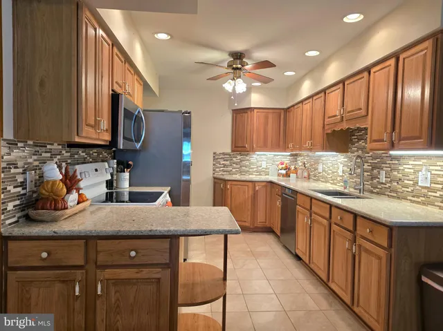 a kitchen with stainless steel appliances kitchen island granite countertop a sink dishwasher a stove and a refrigerator with wooden cabinets