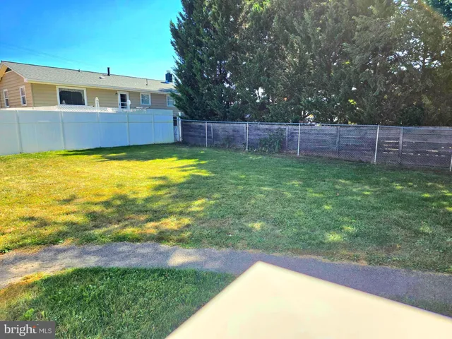 a view of a backyard with wooden fence and large trees