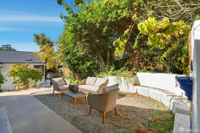 an outdoor sitting area with couch and a garden