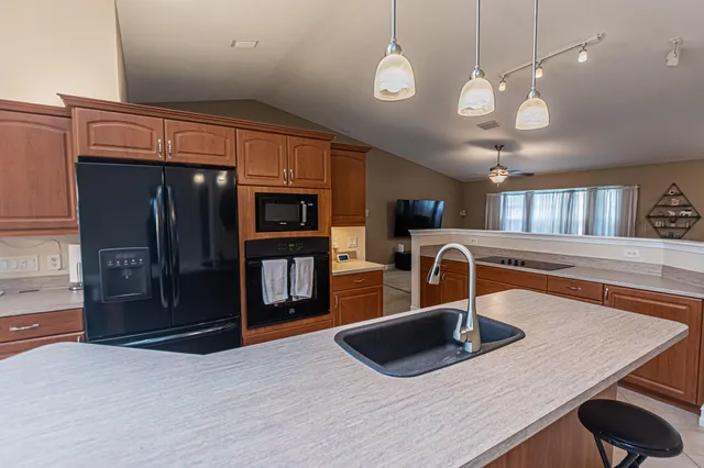 a kitchen with kitchen island a sink stainless steel appliances and a counter top space
