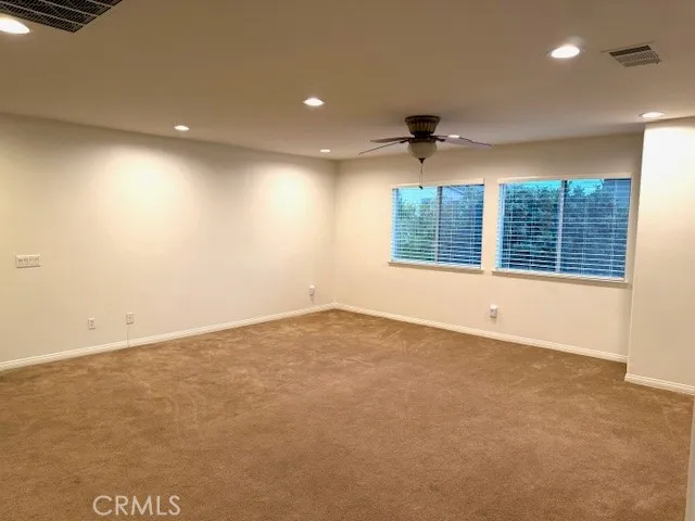 an empty room with windows and ceiling fan