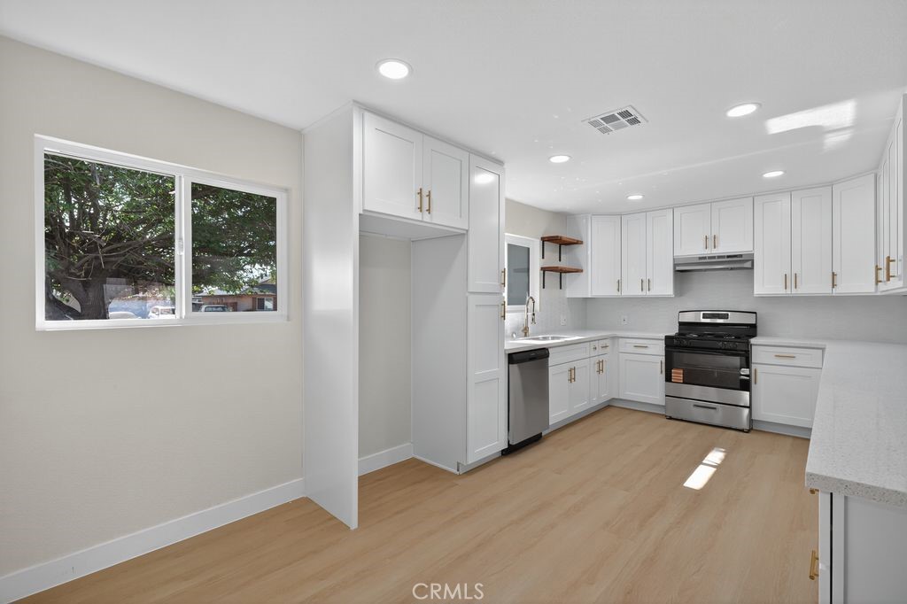 606 East Jackson Street Rialto, CA 92376 - Photo 10 of 29 a kitchen with a refrigerator a stove top oven and white cabinets