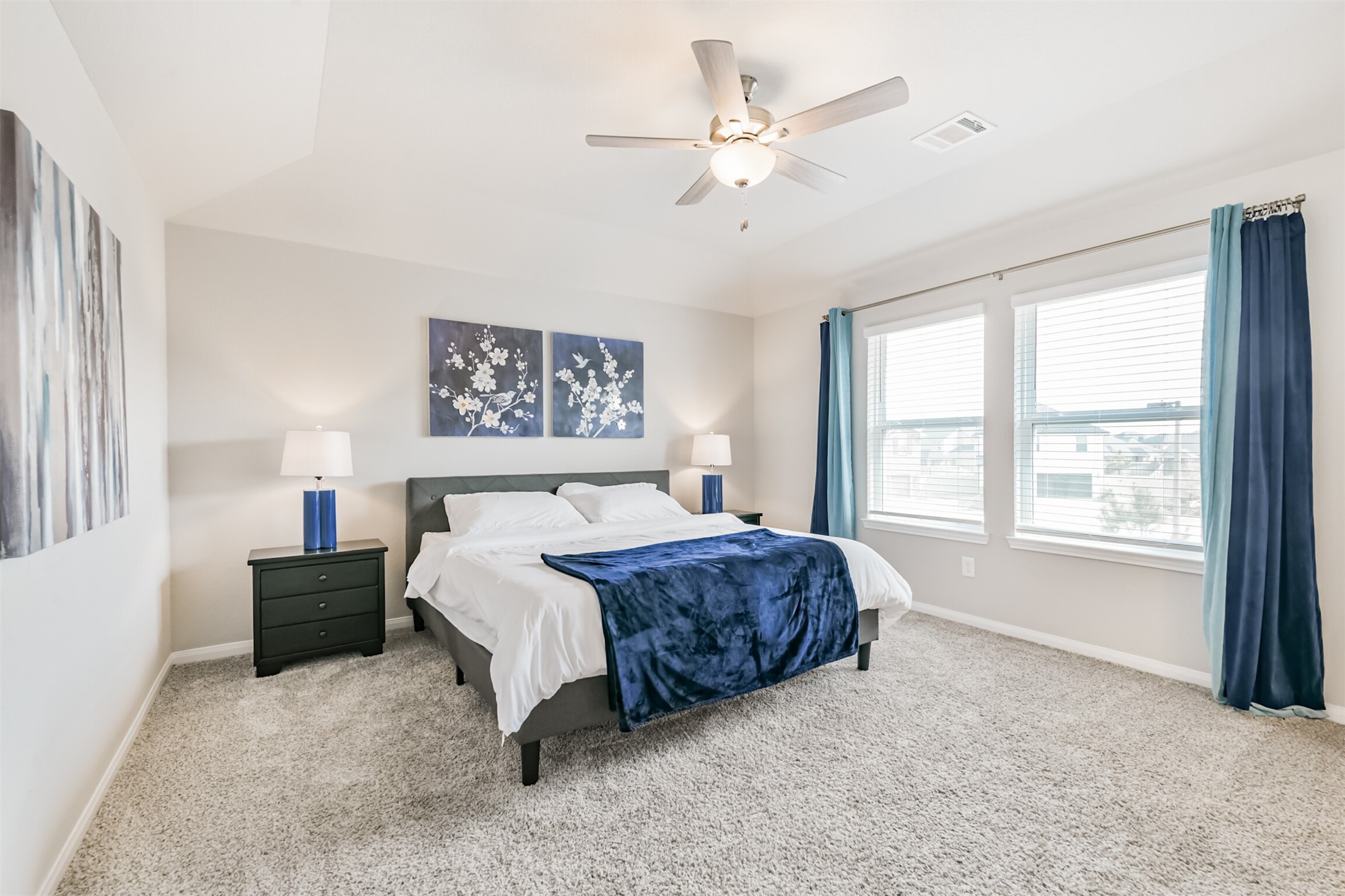 17465 Buckeye Branch Conroe, TX 77385 - Photo 19 of 47 A spacious primary bedroom with neutral carpeting and large windows for natural light. It includes a ceiling fan, cozy bed setup, and access to an en-suite bathroom.