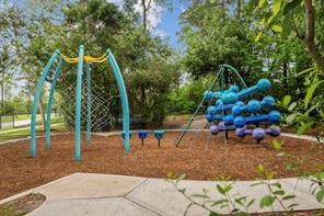 17465 Buckeye Branch Conroe, TX 77385 - Photo 47 of 47 This photo showcases a vibrant playground nestled in a lush, wooded area. It features modern climbing equipment with colorful structures on a soft mulch surface, perfect for family-friendly outdoor fun.