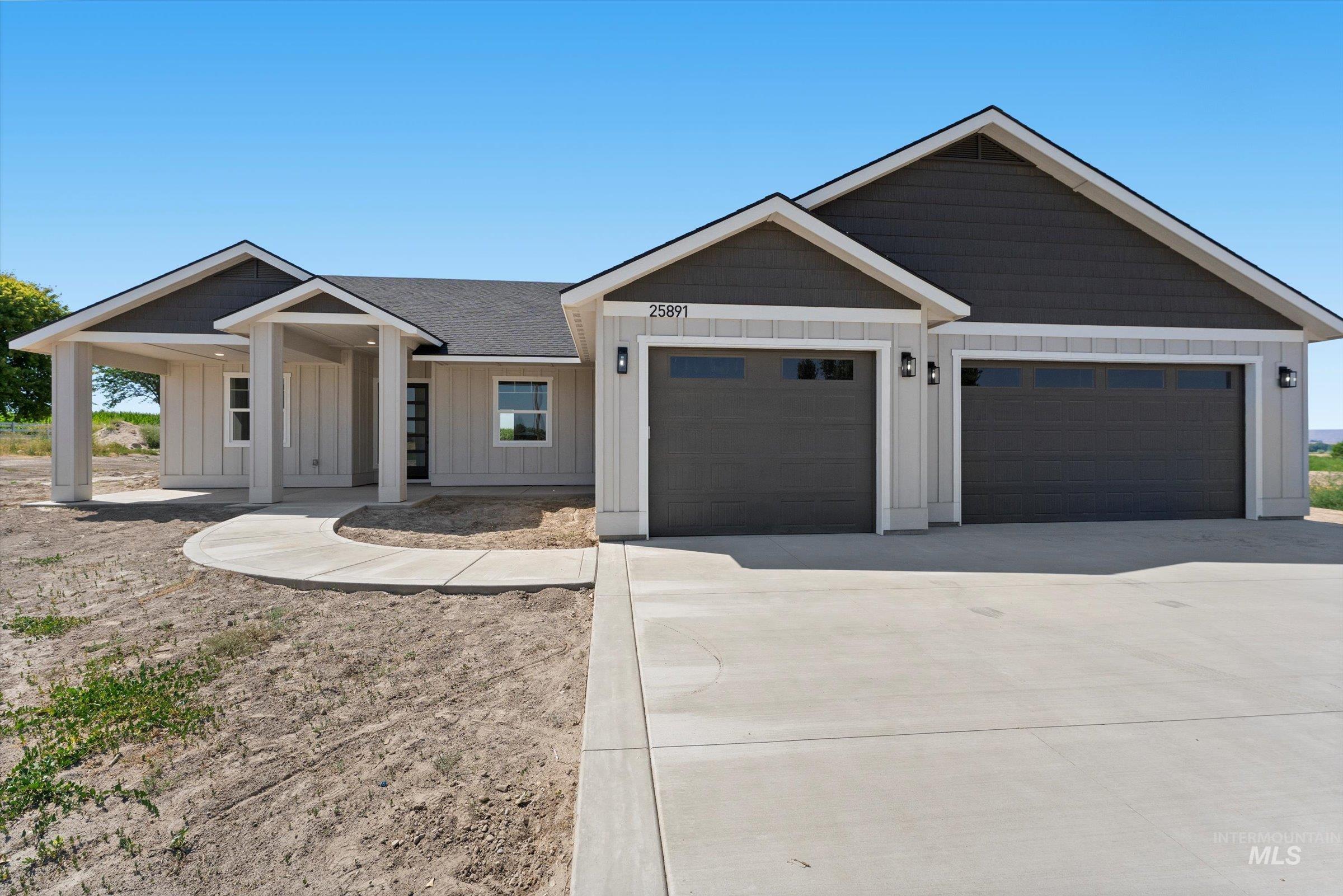 View of front of house with board and batten siding, an attached garage, and driveway