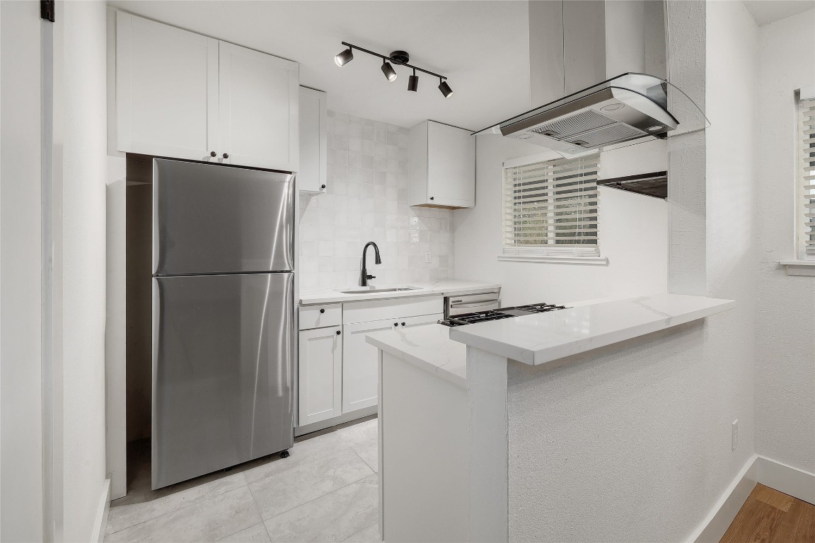 a kitchen with stainless steel appliances a refrigerator a sink and a refrigerator