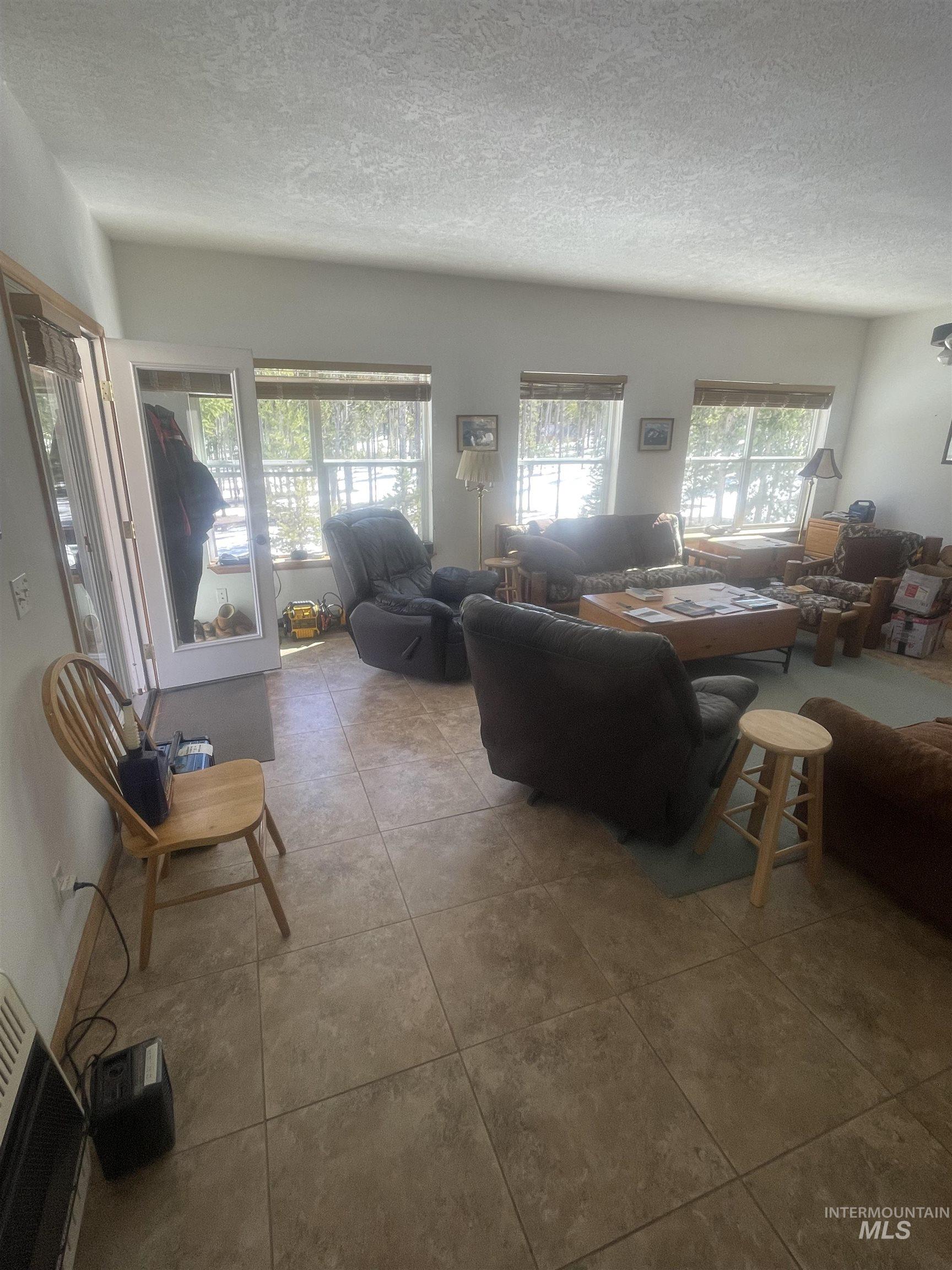 17567 Edwardsburg Road Yellow Pine, ID 83677 - Photo 6 of 11 Living area featuring tile flooring, multiple windows with blinds, and white walls