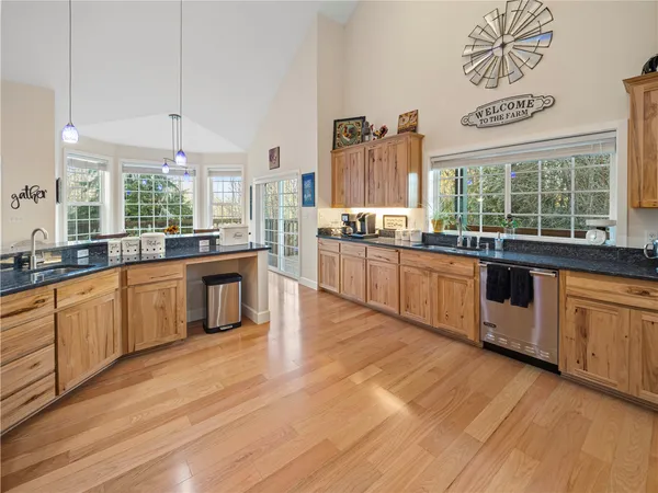 a large kitchen with stainless steel appliances granite countertop a large counter top a stove and a wooden floors