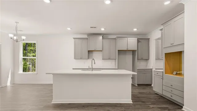 a large white kitchen with kitchen island a sink stainless steel appliances and cabinets