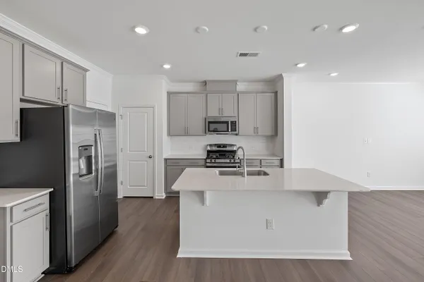 a kitchen with a refrigerator a stove top oven and wooden floor