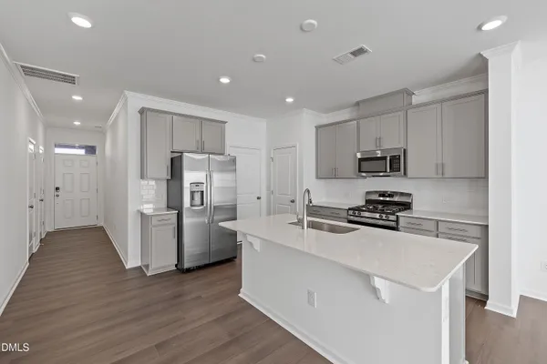 a kitchen with stainless steel appliances a refrigerator a stove a sink cabinets and wooden floor